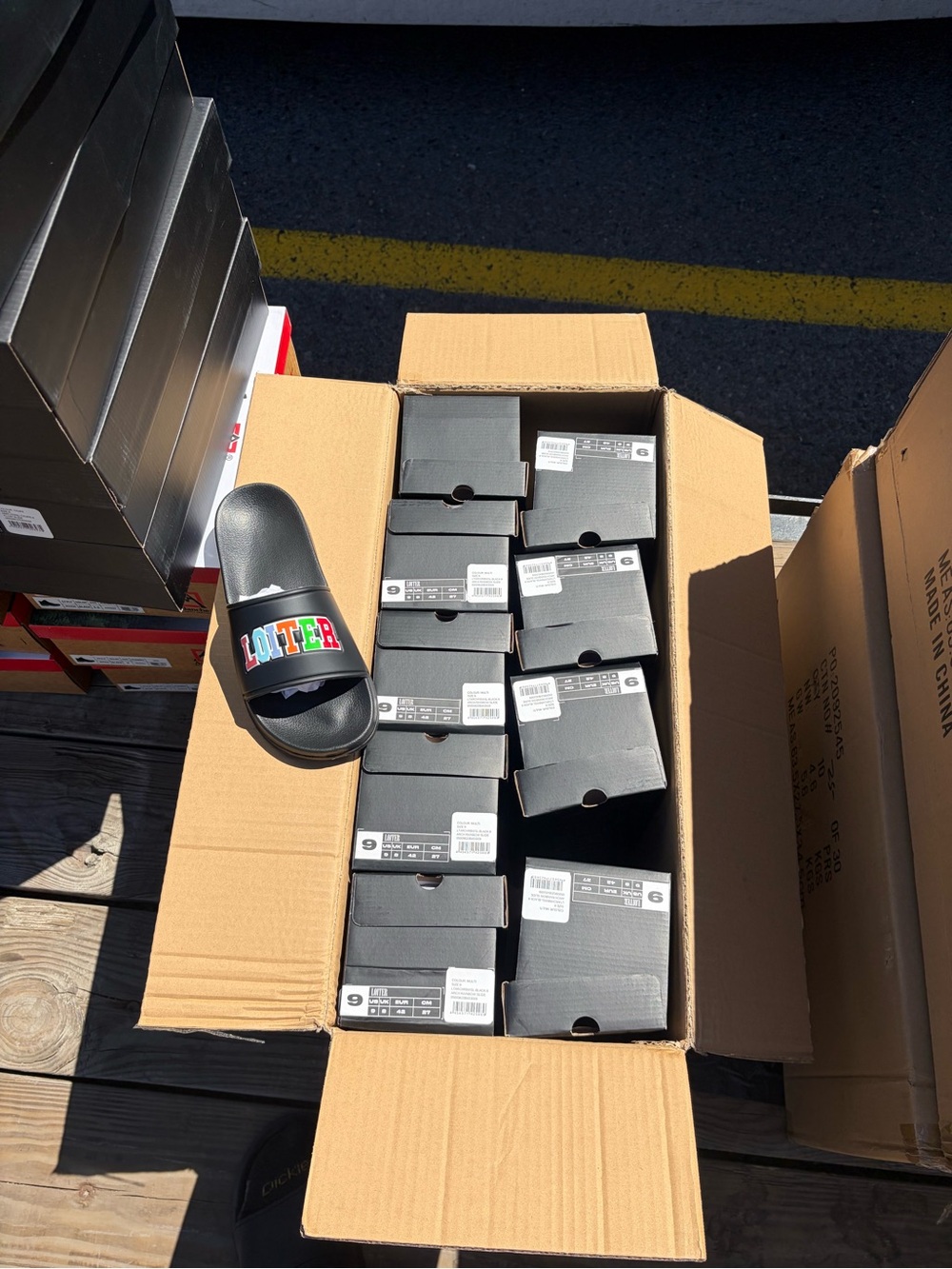 Black slides with rainbow “ LOITER ” Logo